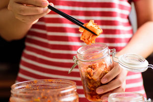 Some Homemade Kimchi being pulled from a jar, a rich, natural source of probiotics