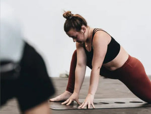 A lady is stretching her hip flexor peacefully in a gym class